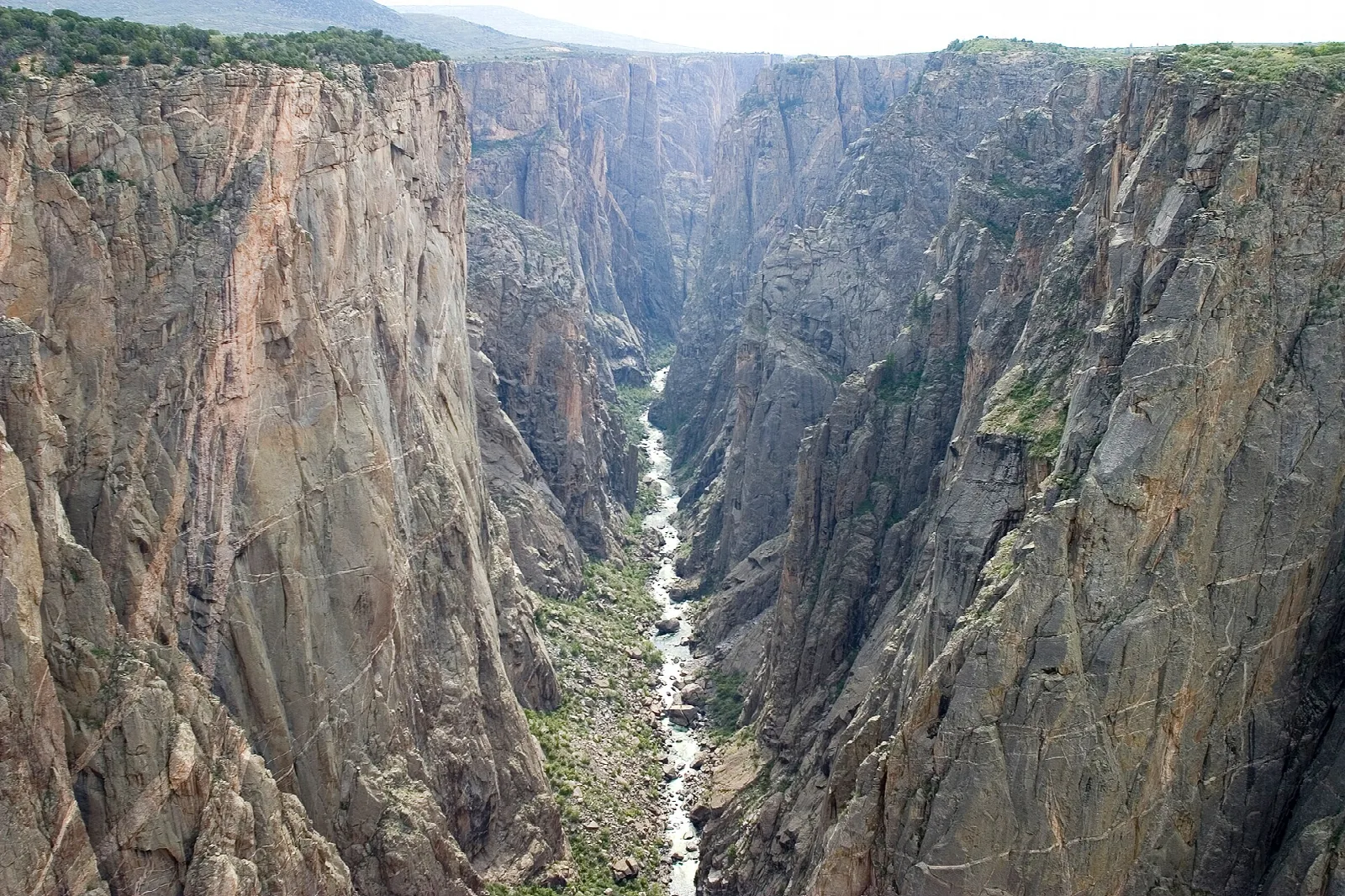 Narrow black canyon with nearly vertical walls and a white-water river at the bottom