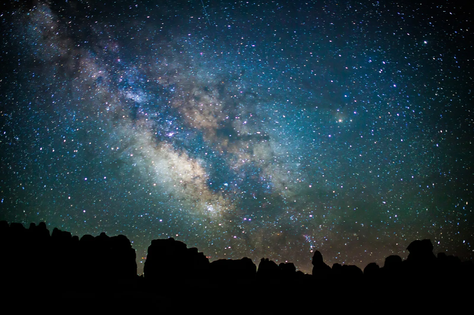 The Milky Way arching over the silhouetted spires of the Needles