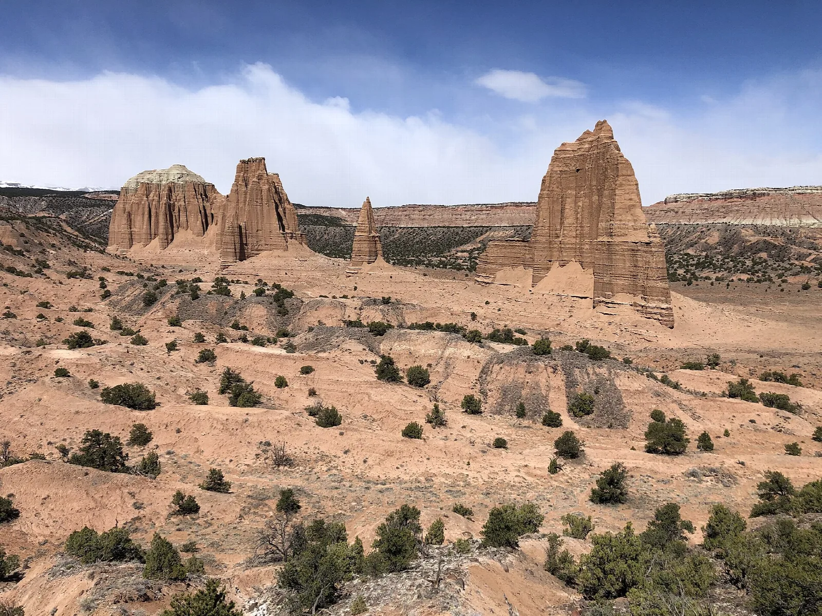 Tall, narrow sandstone monoliths rising from a desert valley under a blue sky