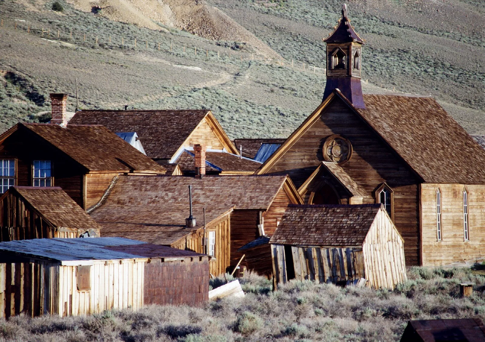Weathered wooden church and buildings in a sagebrush valley