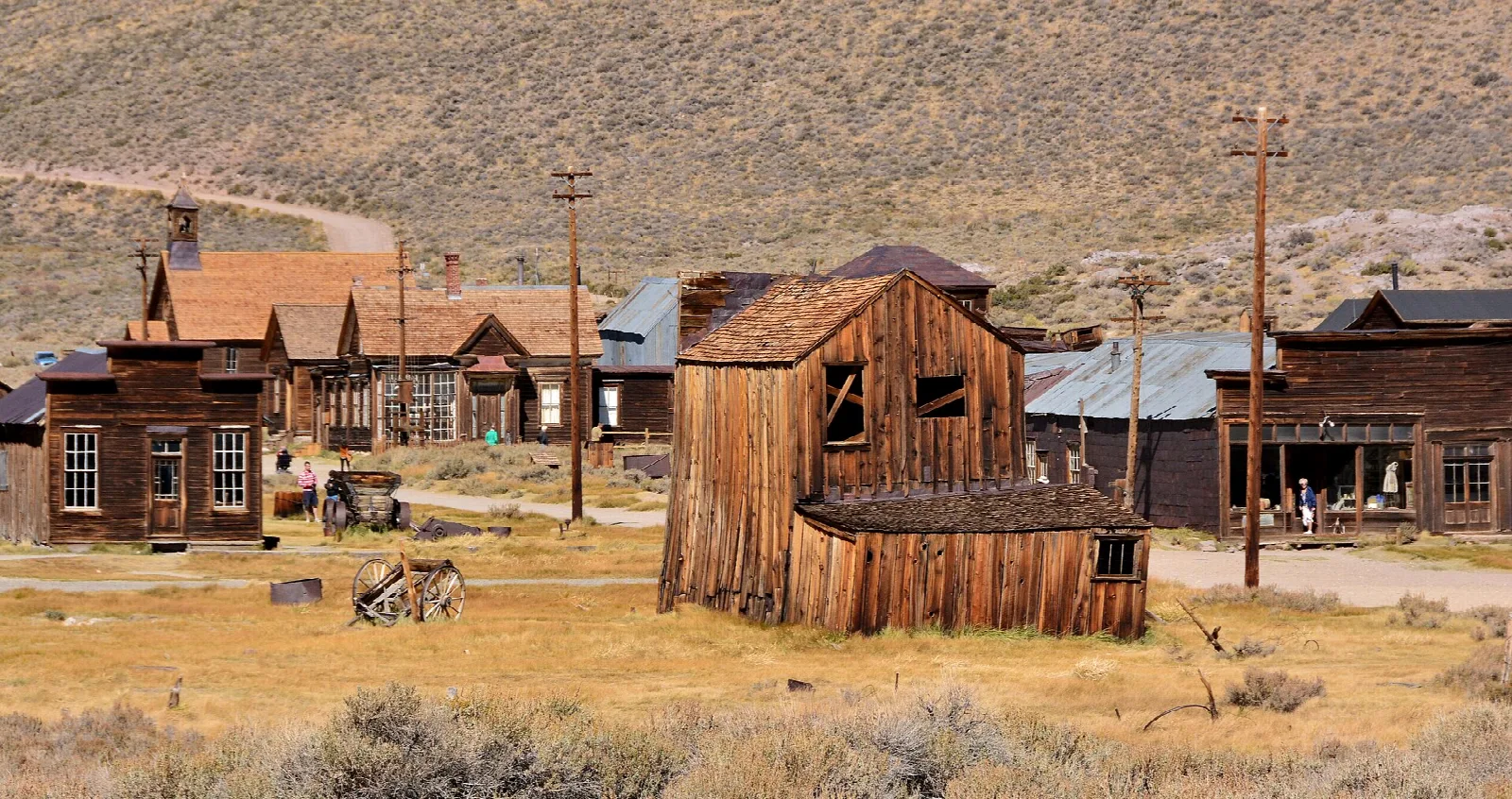 Row of old wooden buildings on a dry plain with hills behind
