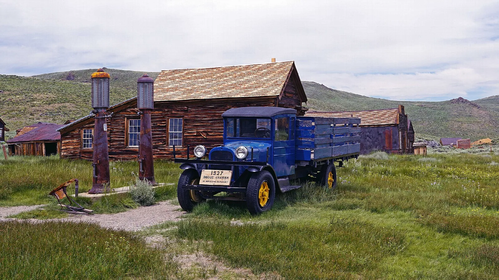 Vintage blue truck and gas pumps beside a wooden building