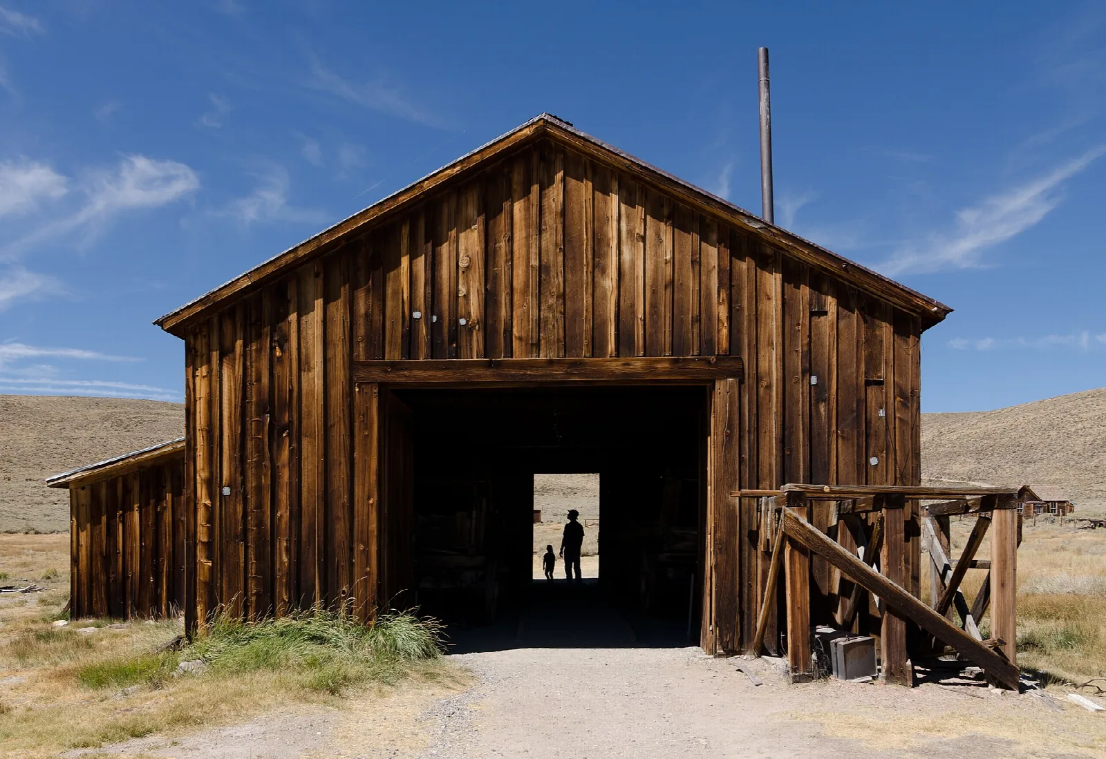 Large wooden barn with an open door and a person inside