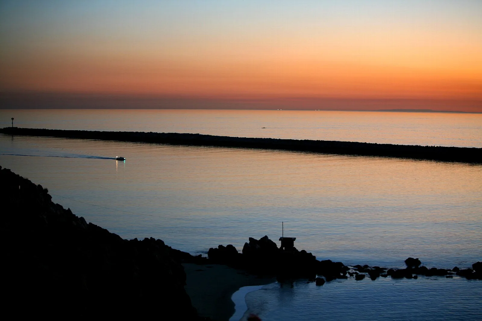 Jetty and rocky shore silhouetted at sunset