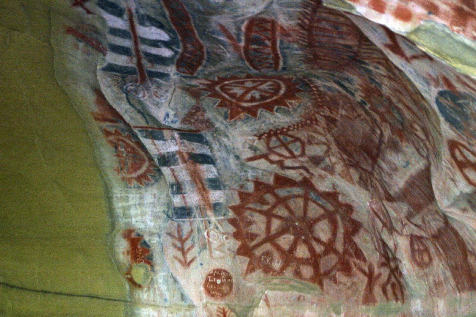 Red and black Chumash paintings on a pale rock wall