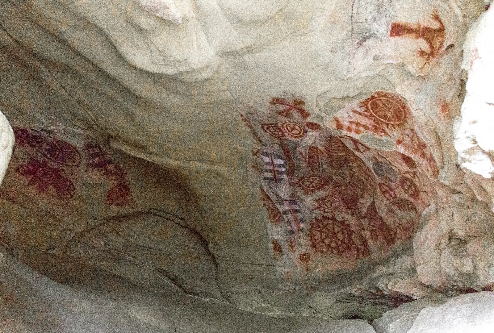 Red painted designs on the curved wall of the cave