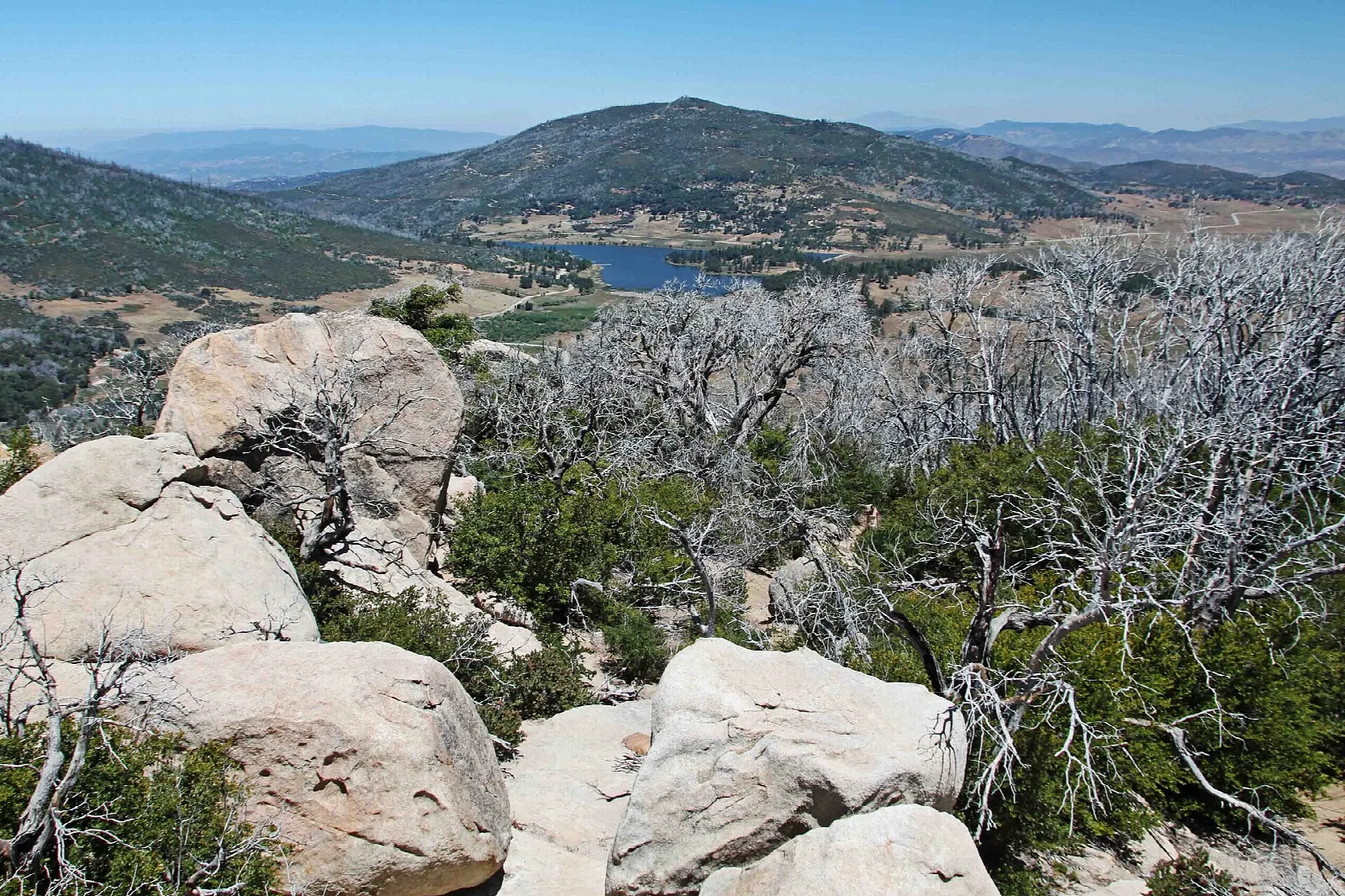 Granite boulders and bare trees above a lake in the valley