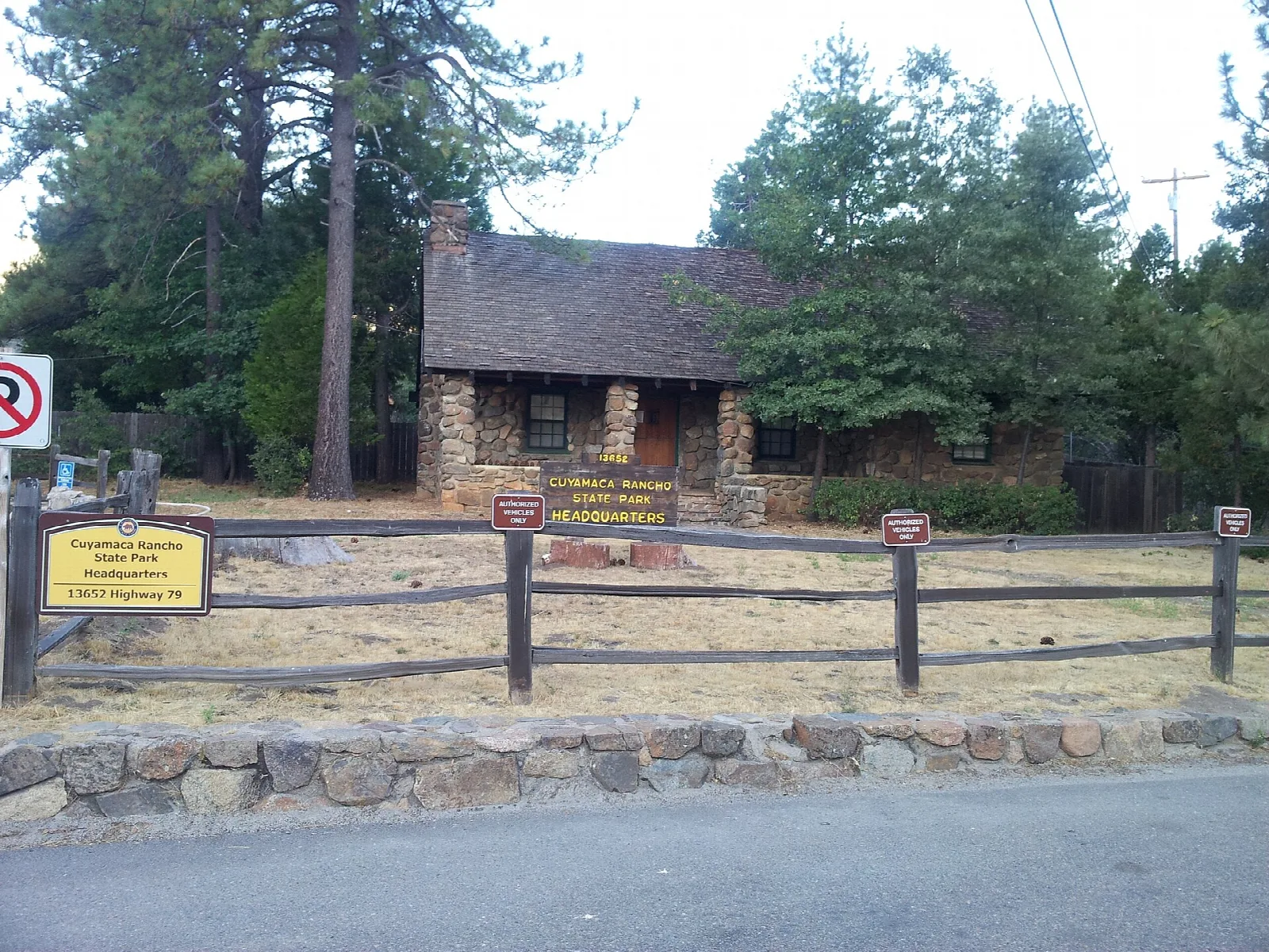 Stone headquarters building behind a split-rail fence and pines