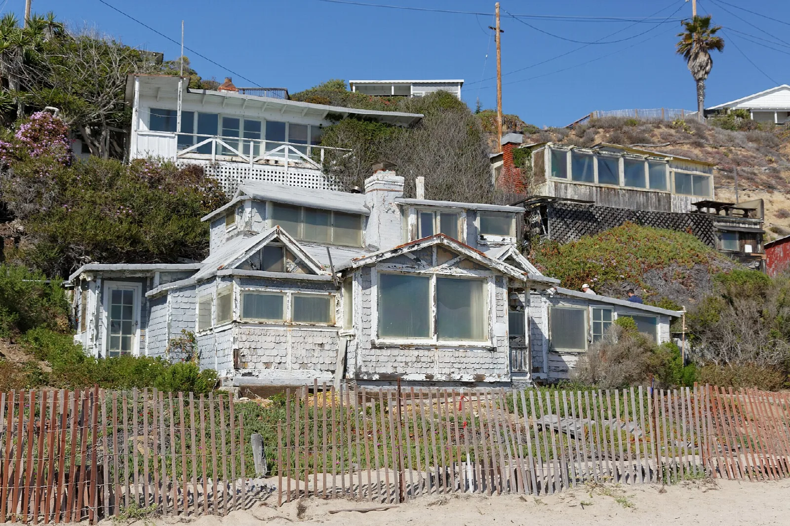 Weathered gray beach cottage behind a wooden fence