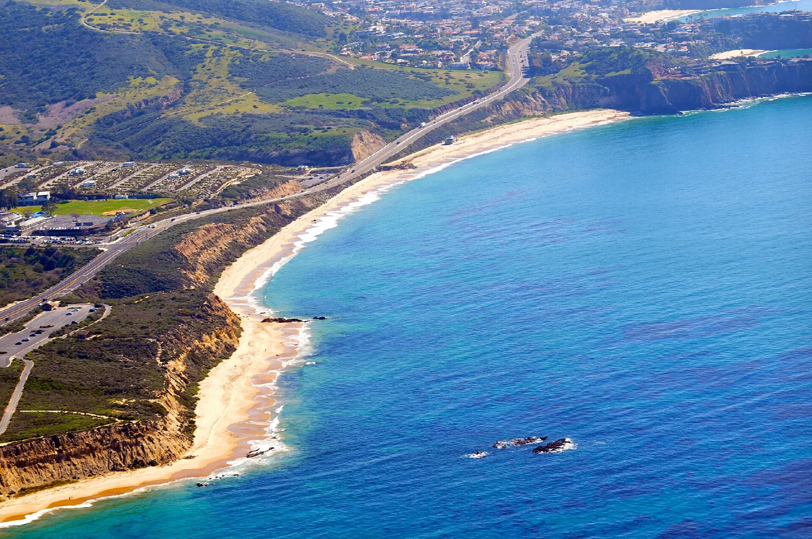 Aerial view of a curving beach, blue water and coastal bluffs