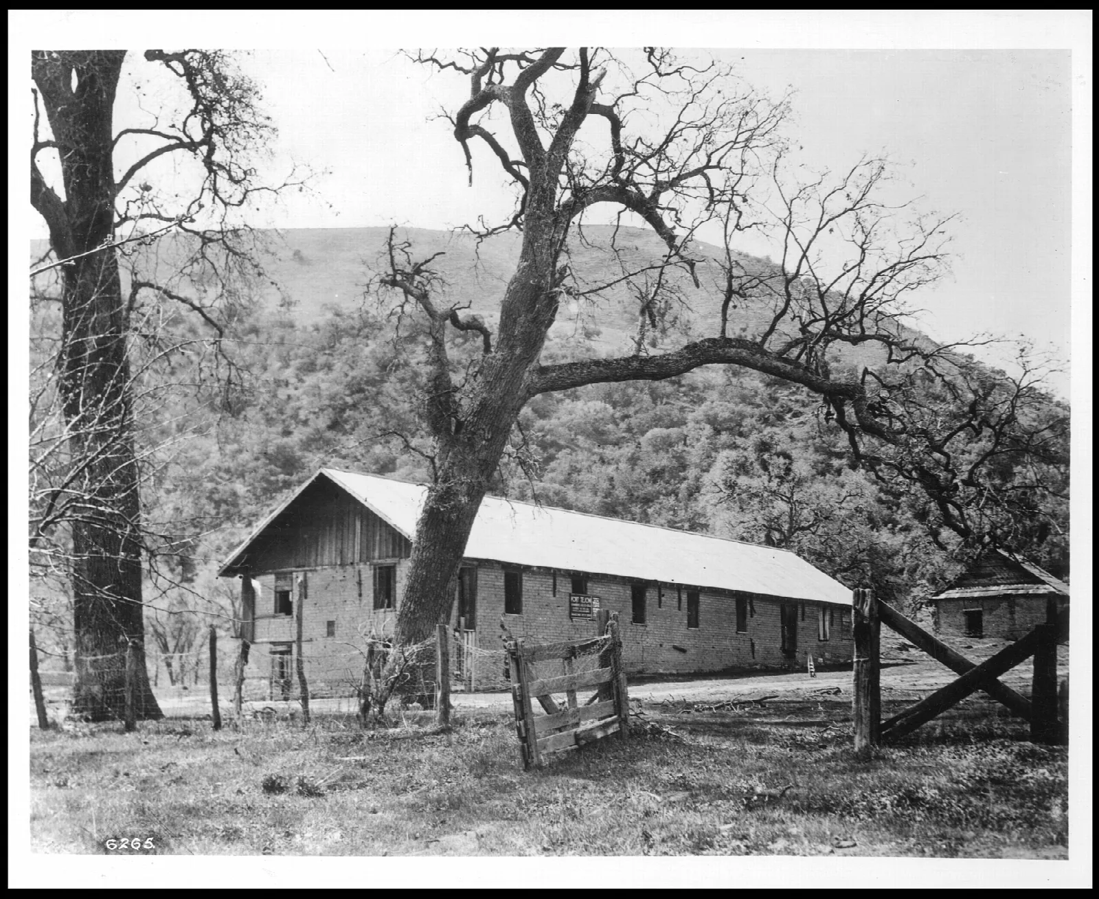 Black and white photo of the main barracks building among oaks