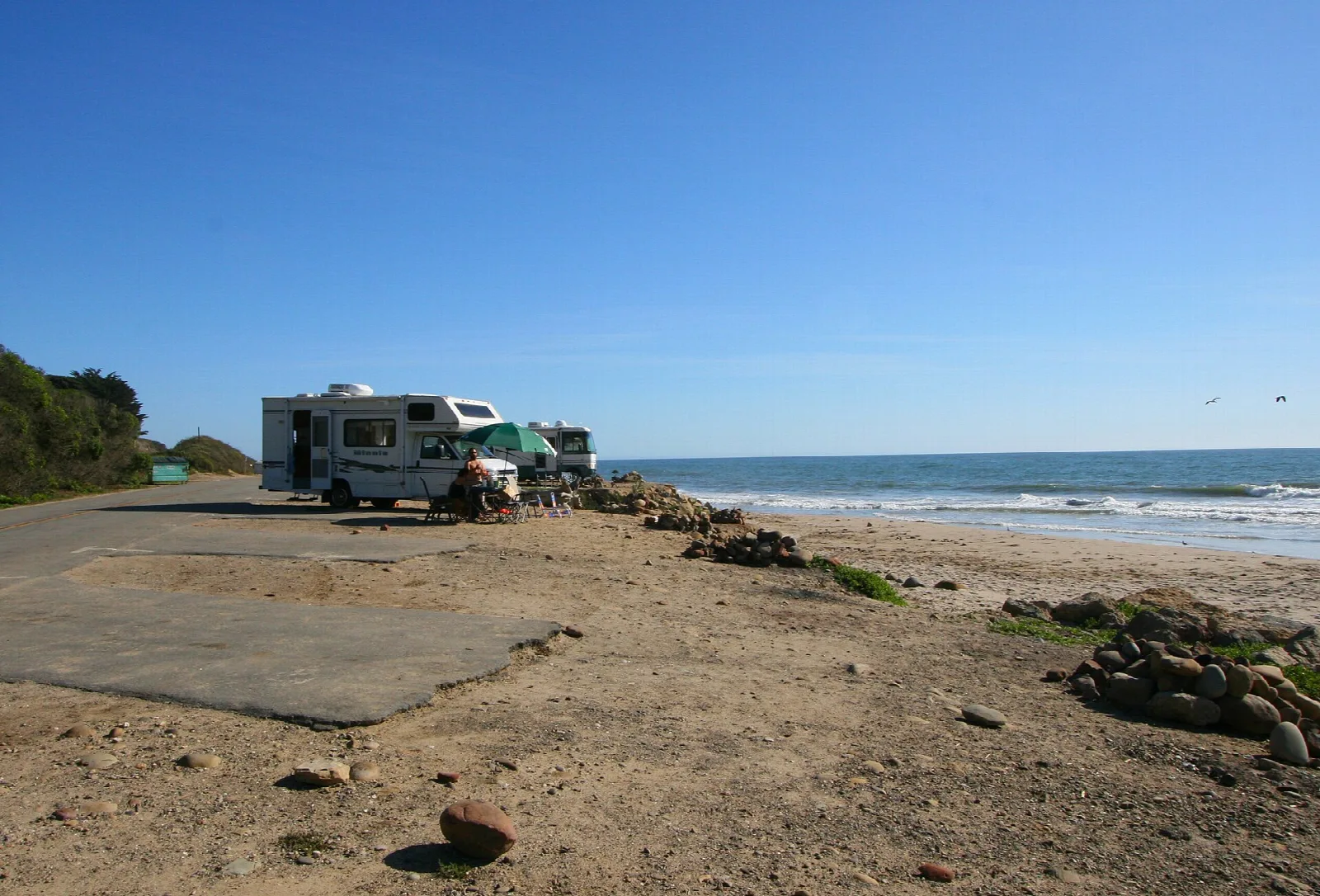Empty beachside campsites with a motorhome and the ocean beyond