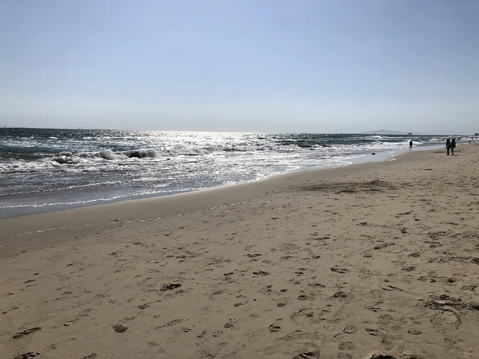 Wide sandy beach with surf under a clear sky