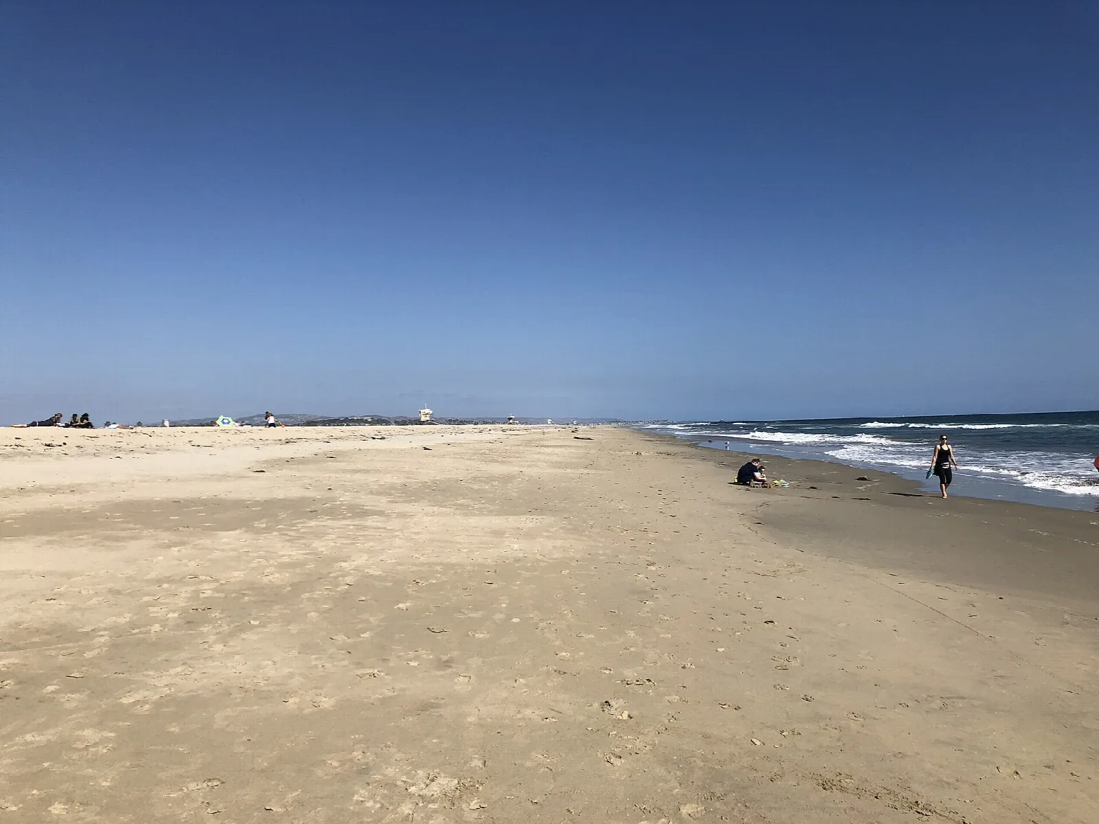 Wide sandy beach meeting the sea under a clear blue sky
