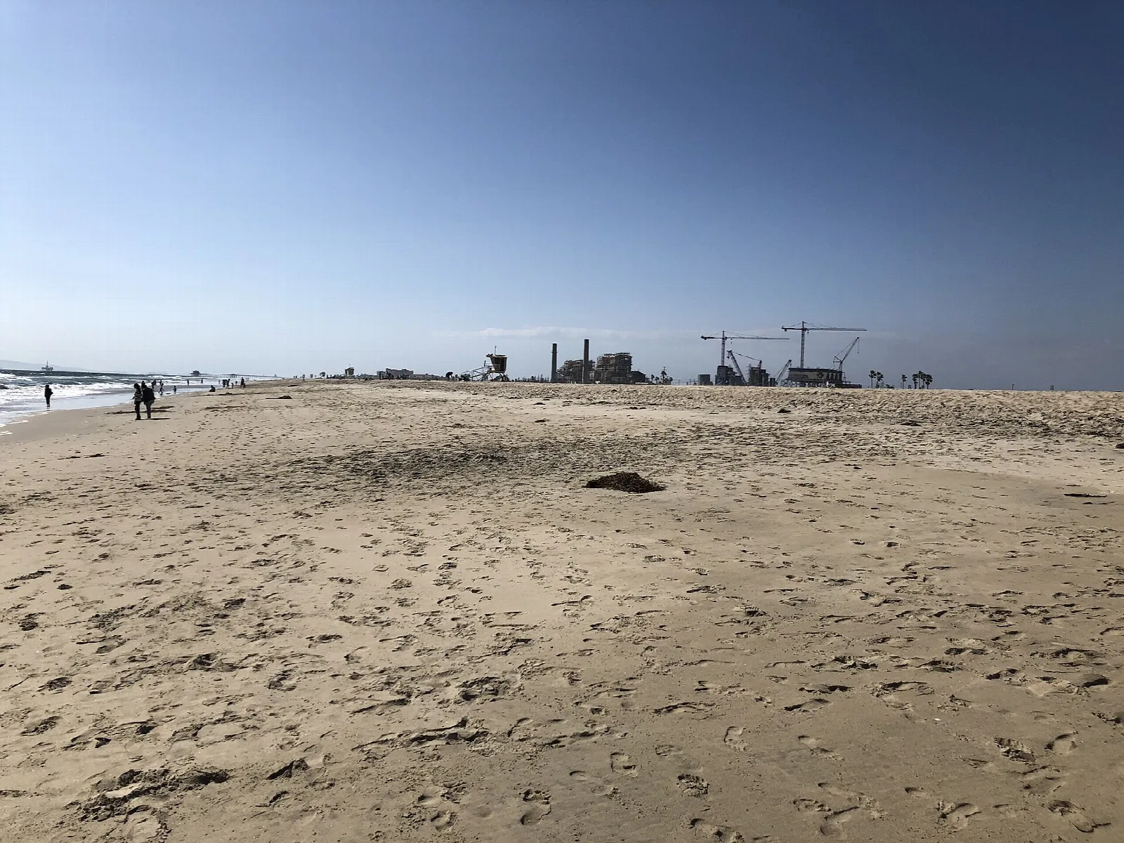 Flat sandy beach with distant buildings and people