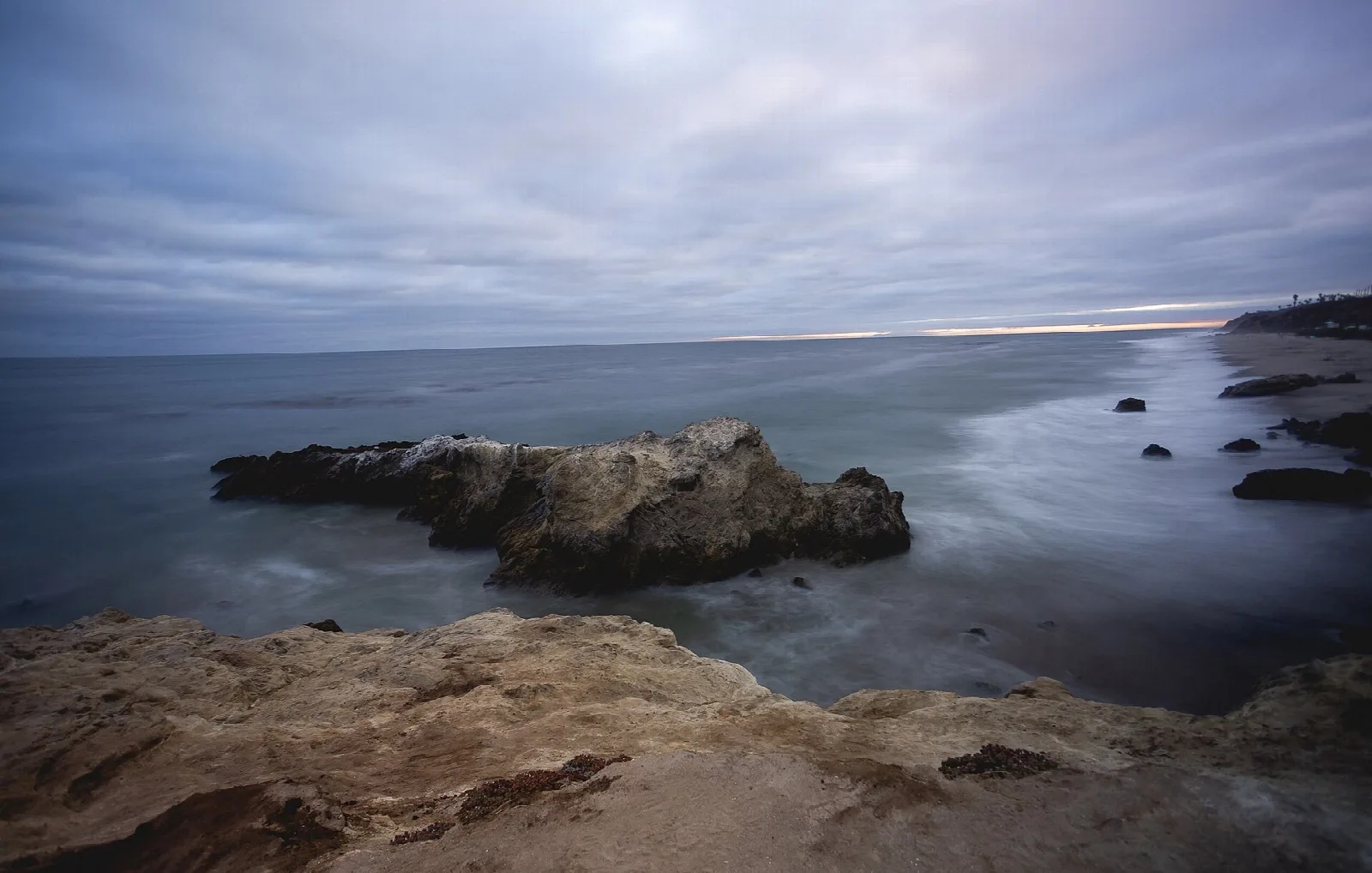 Dark rock outcrop at the water's edge under a stormy sky
