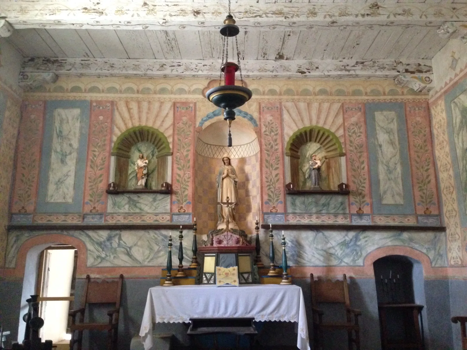 Painted altar with a statue and candle lamp inside the chapel