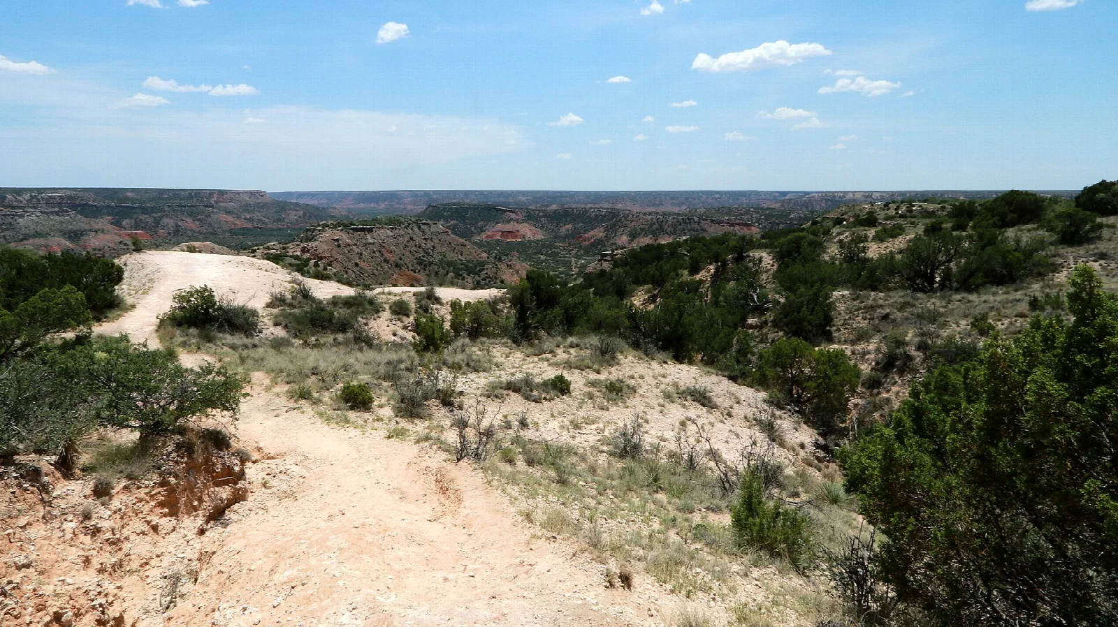 Sandy trail along a canyon rim looking out over the canyon
