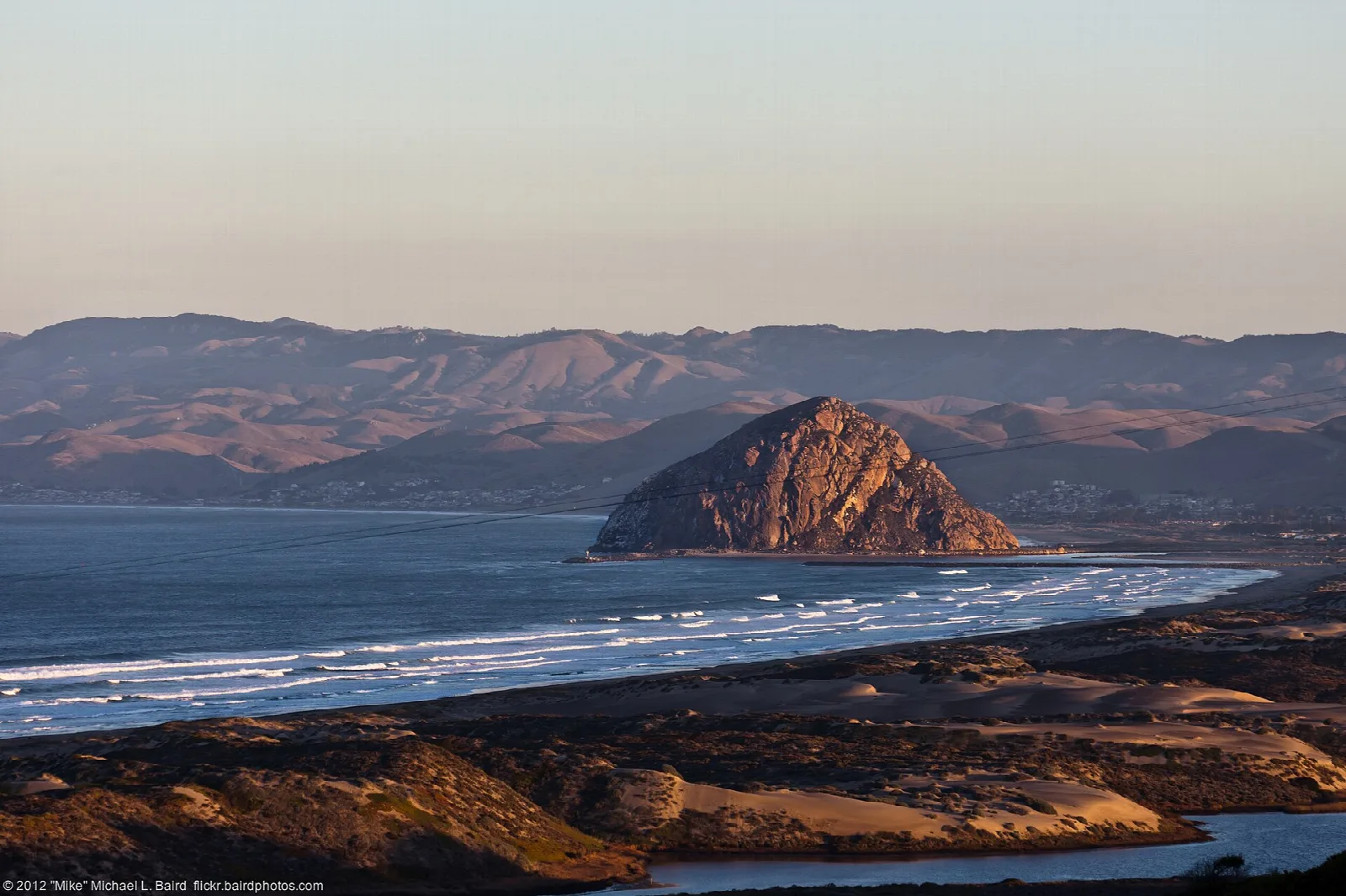 Morro Rock rising from the bay with mountains behind at golden hour