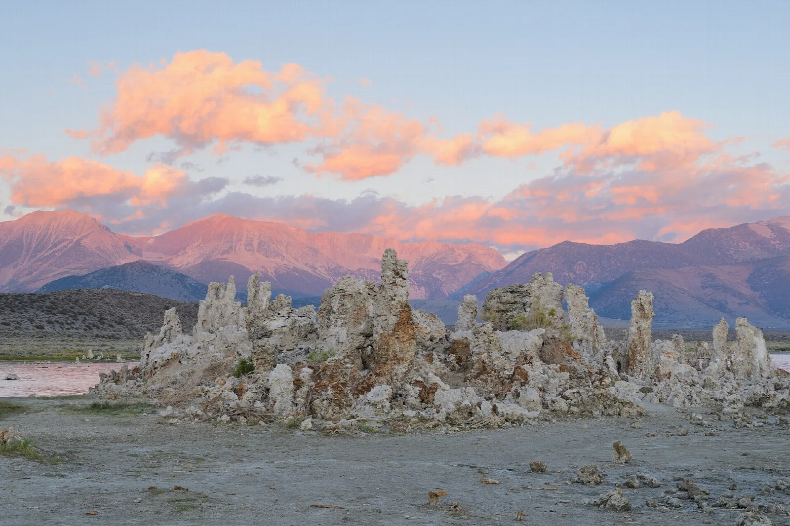 Tufa spires under pink clouds with mountains behind