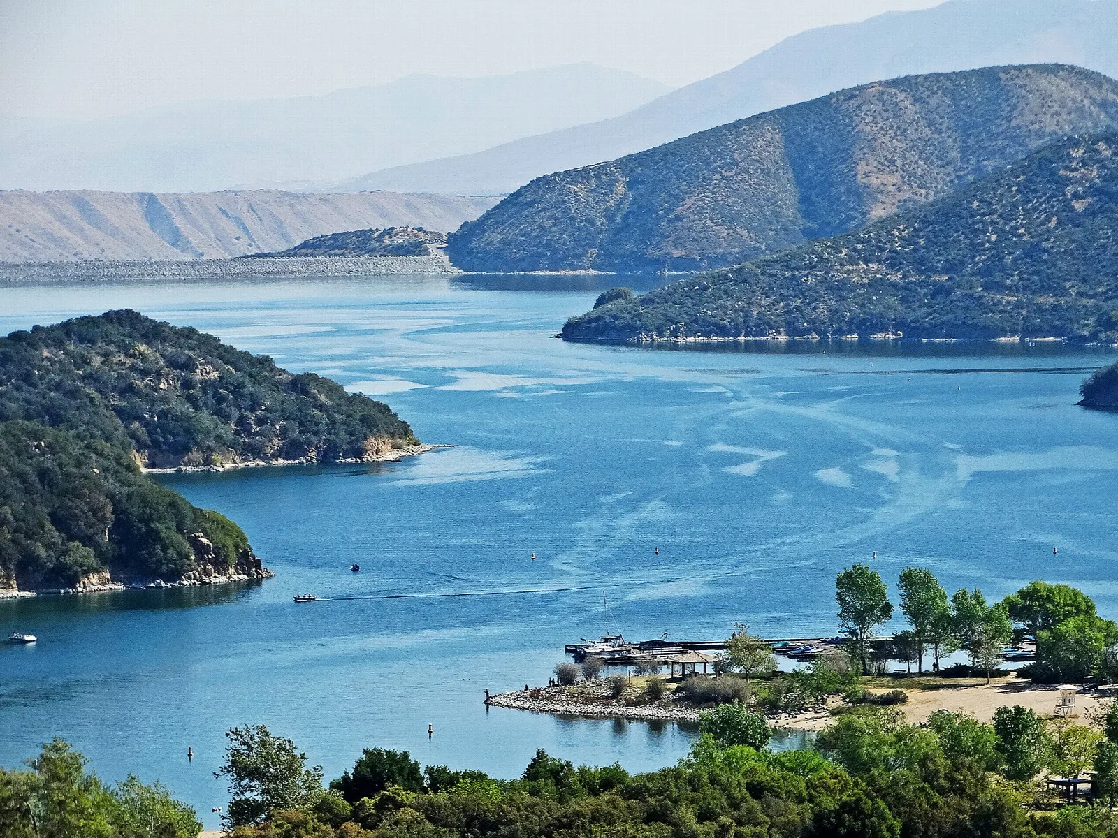 Blue lake with wooded points and distant mountains seen from above