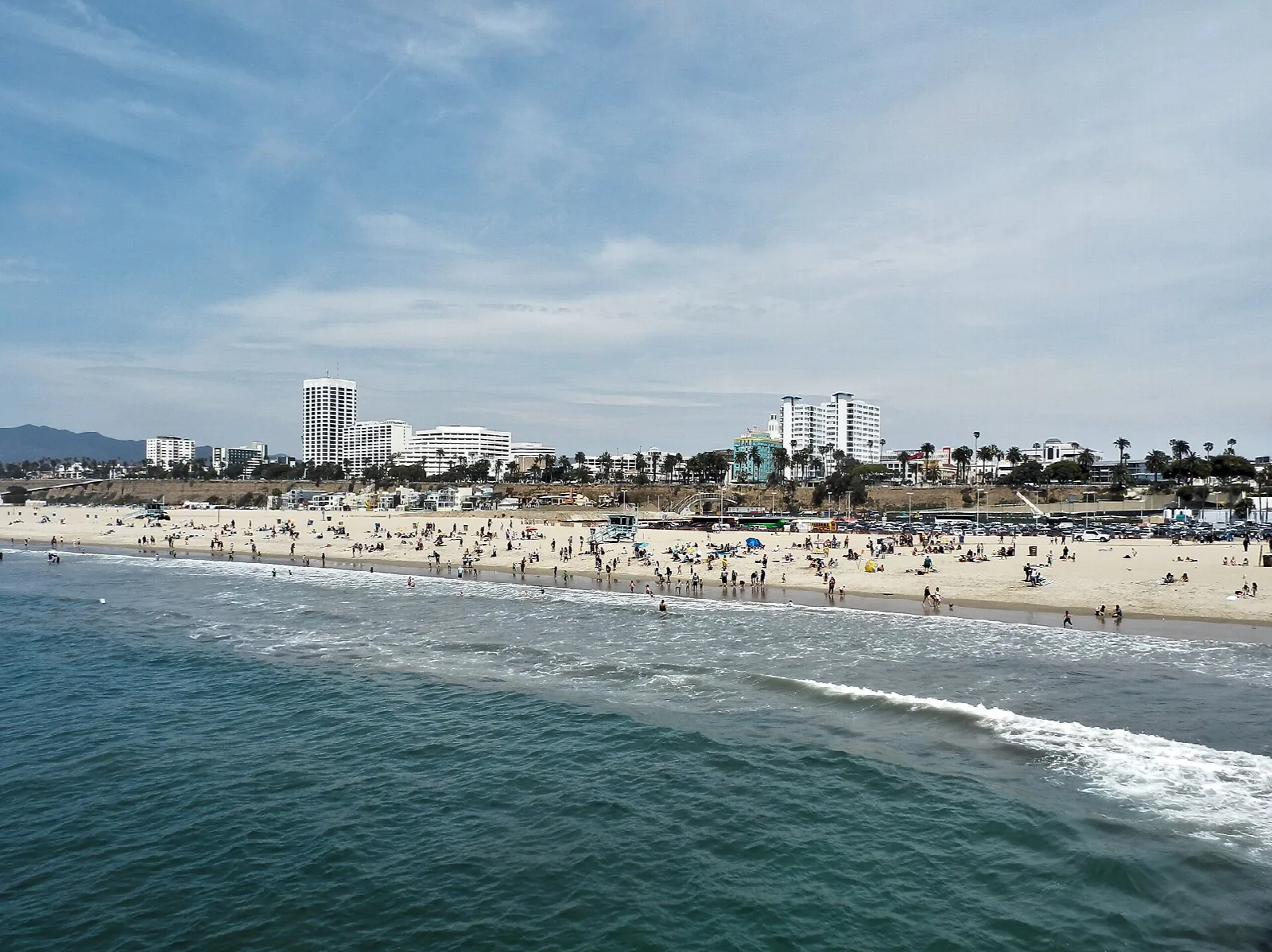 Wide sandy beach with surf and city buildings along the shore