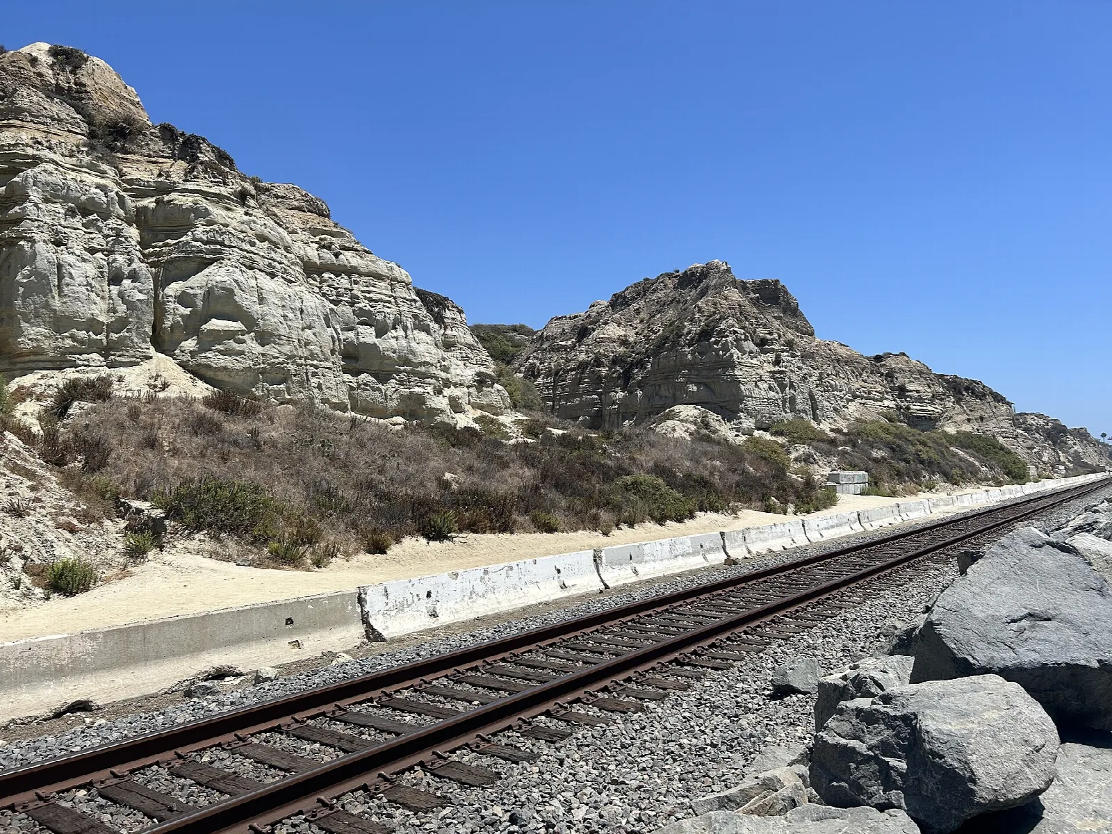 Rugged pale cliffs above a railway line beside the beach