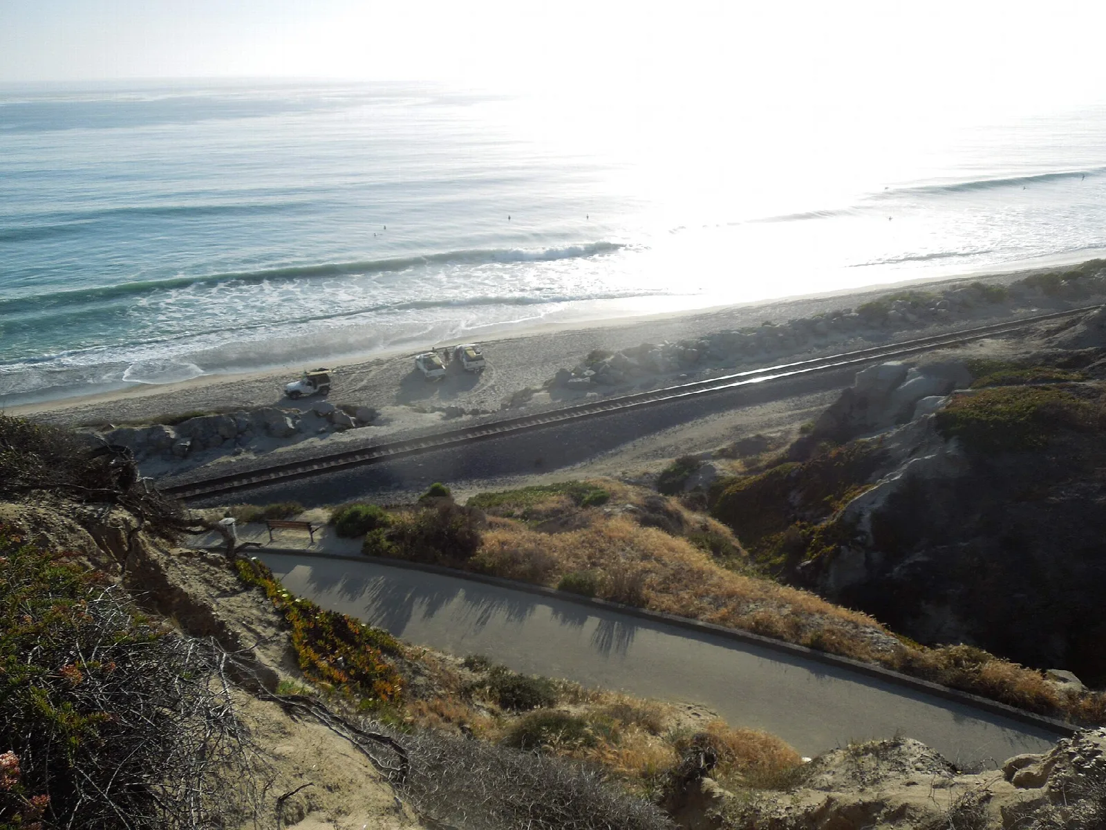 Railroad tracks running along a bluff above the beach in bright sun