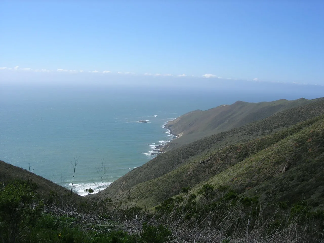 Green coastal ridgeline dropping to a turquoise sea