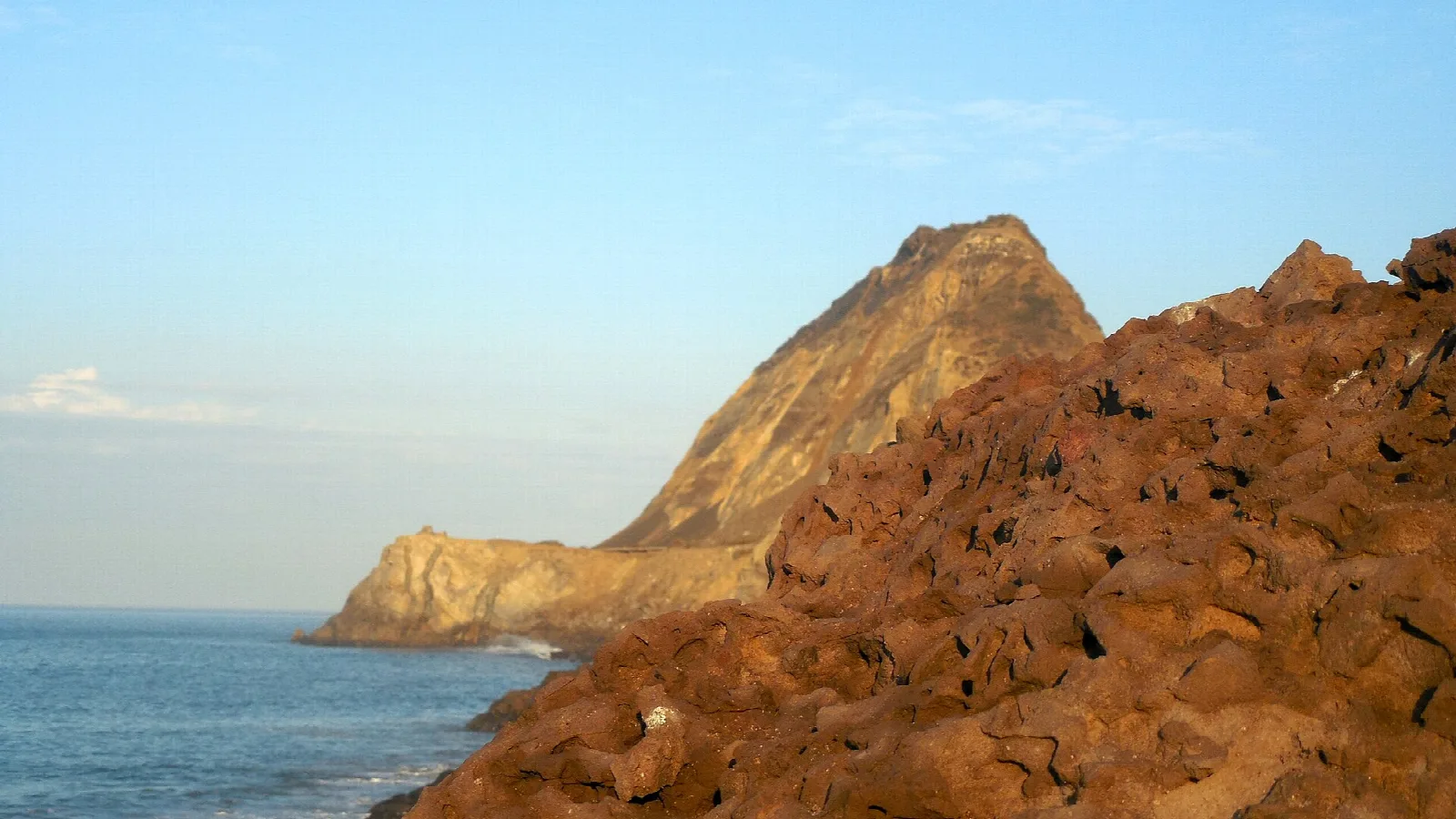 Reddish rocks and a headland at the water's edge