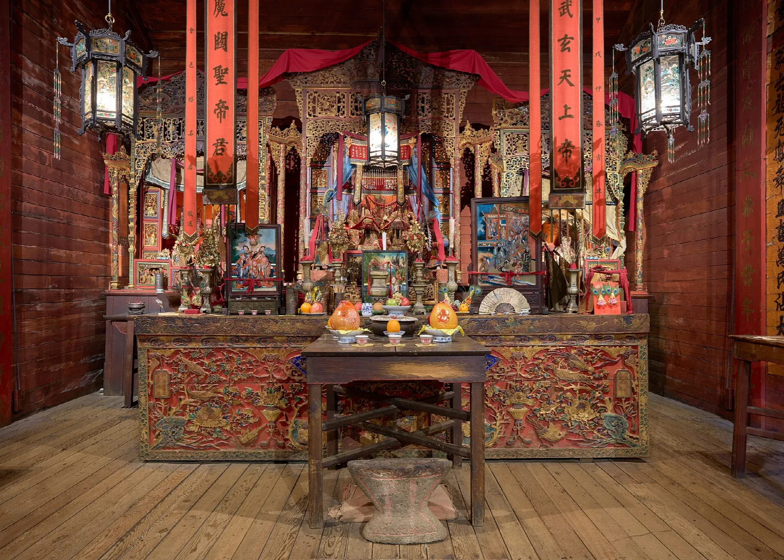 Temple interior with an ornate carved altar and hanging lanterns