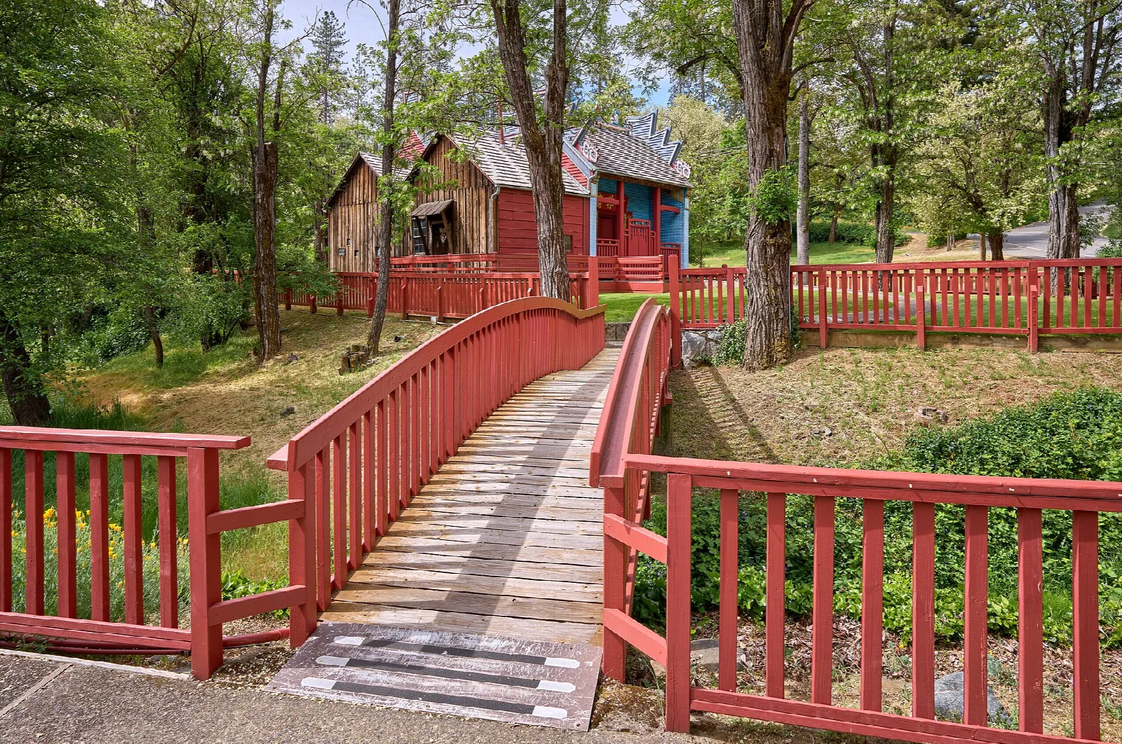 Red-railed wooden bridge leading to the temple through trees