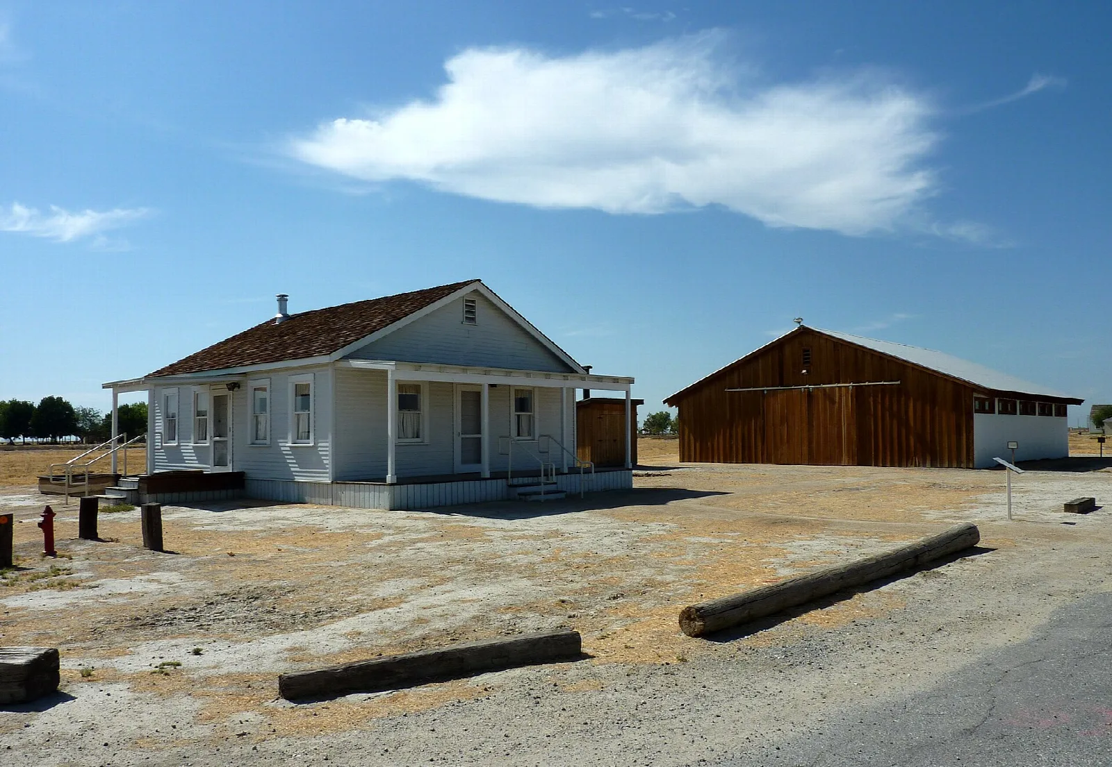 Wood-frame house and red barn on open ground