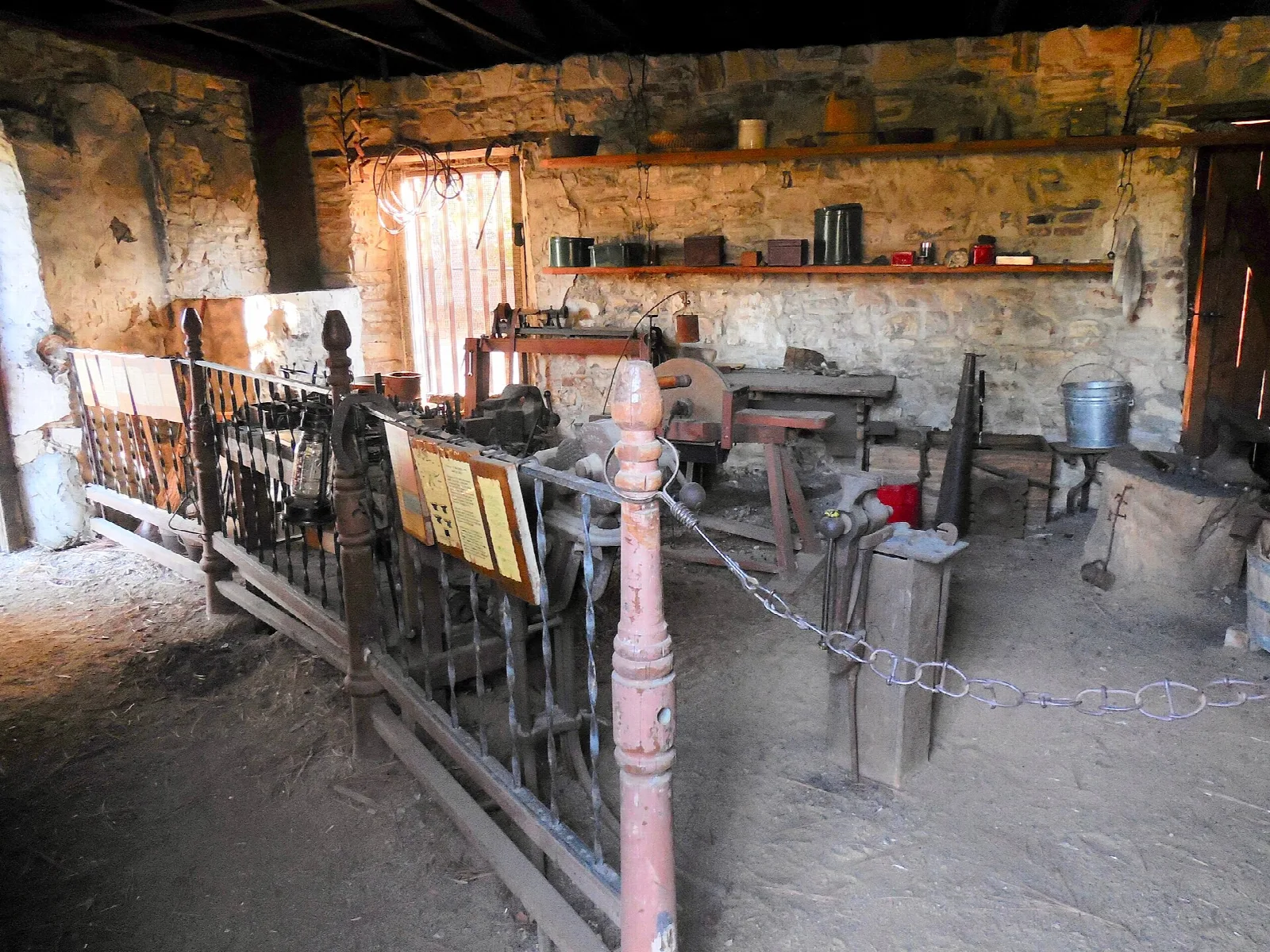 Dim stone workshop with tools and an iron railing