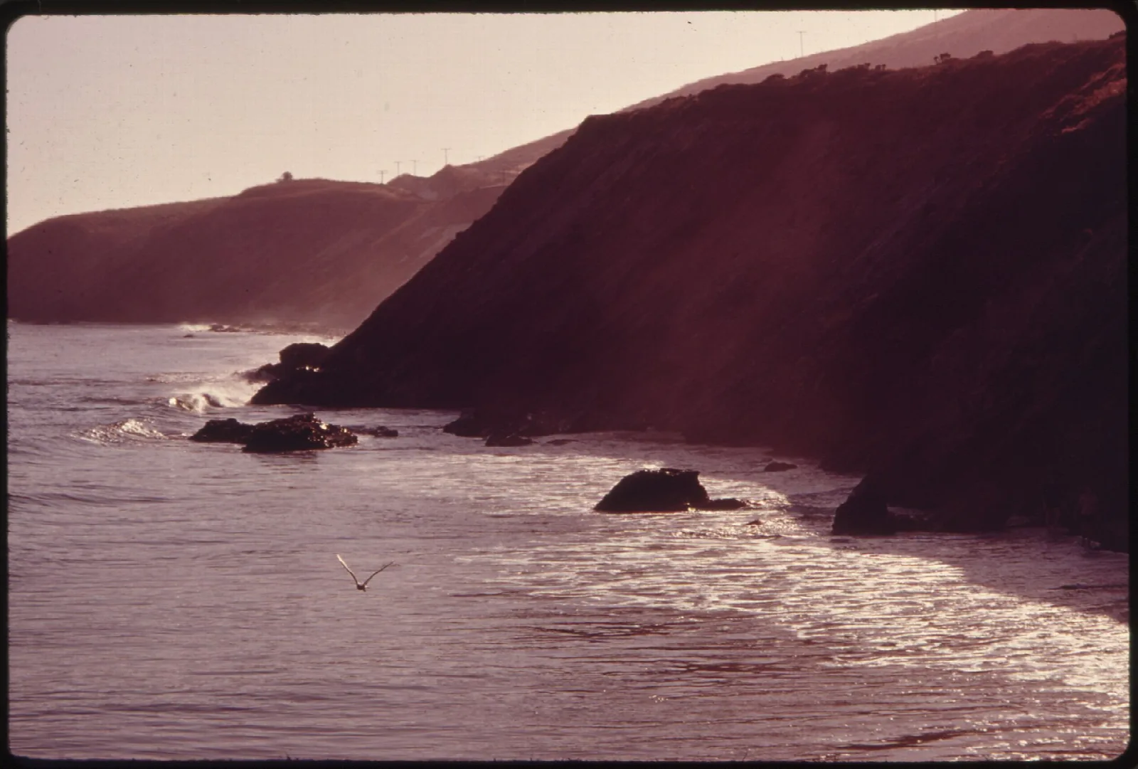 Faded vintage photo of dark headlands and surf