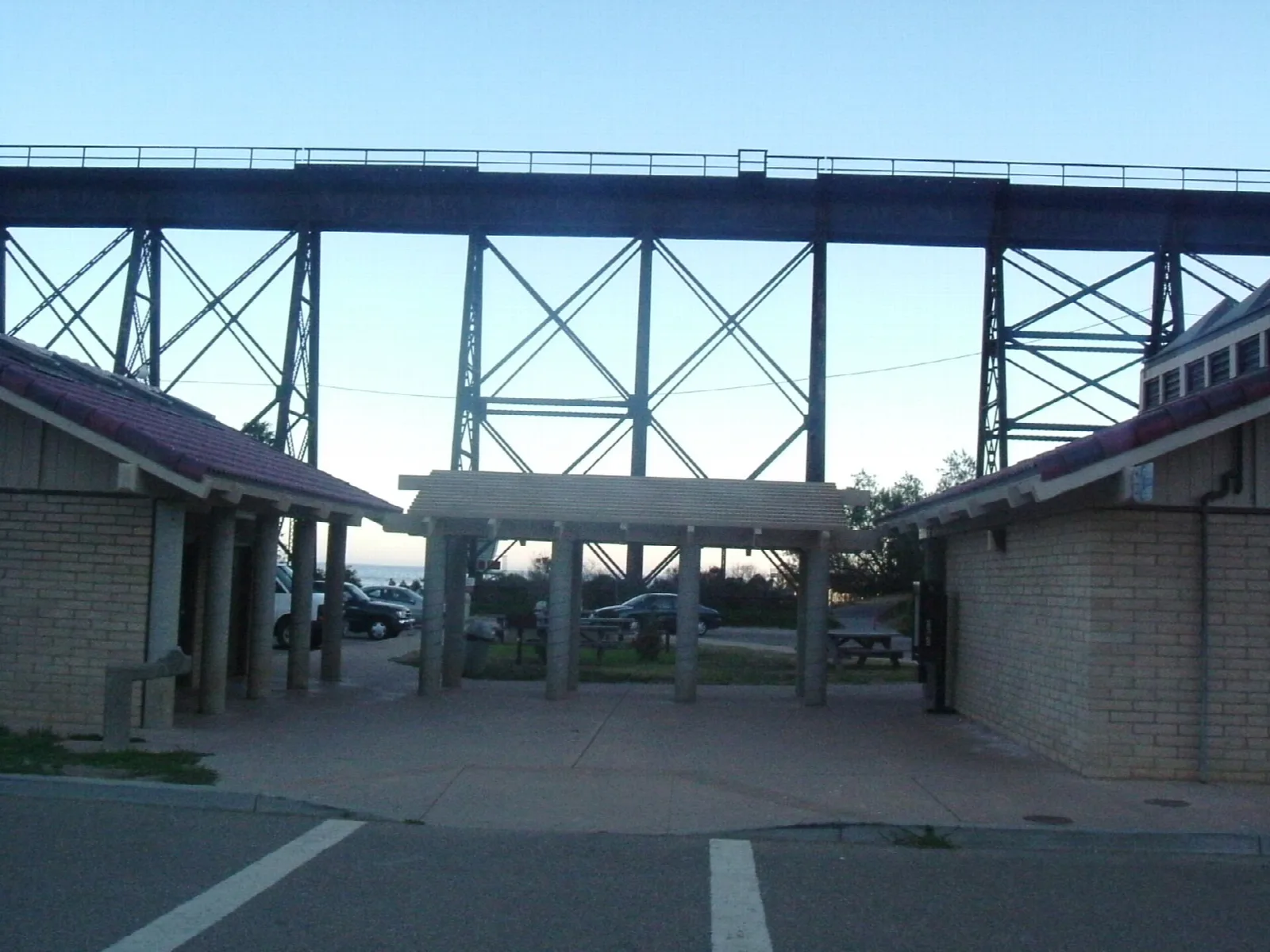 Steel railroad trestle above a covered walkway and beach restrooms