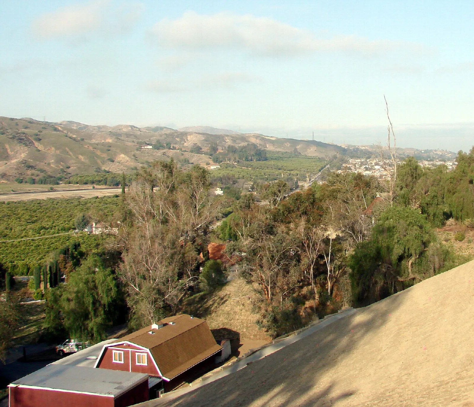 Canyon hills and groves with a red barn in the lower corner