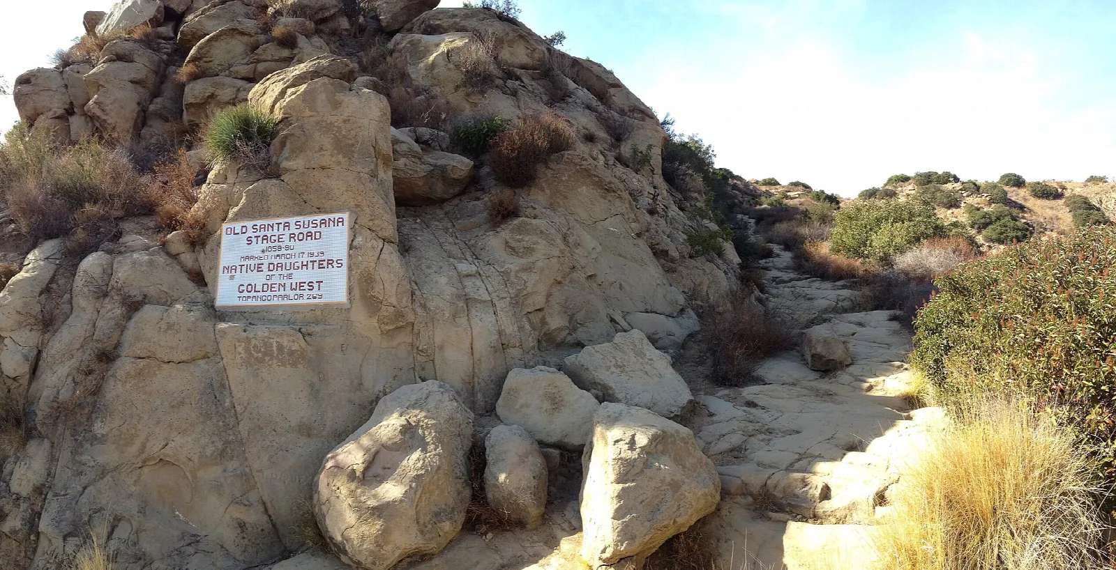 Sandstone outcrop beside a dirt path with a small plaque on the rock