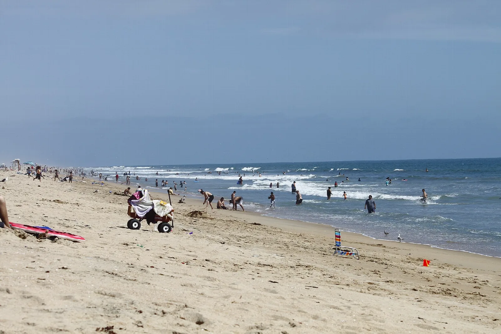 Wide sandy beach with people along the surf