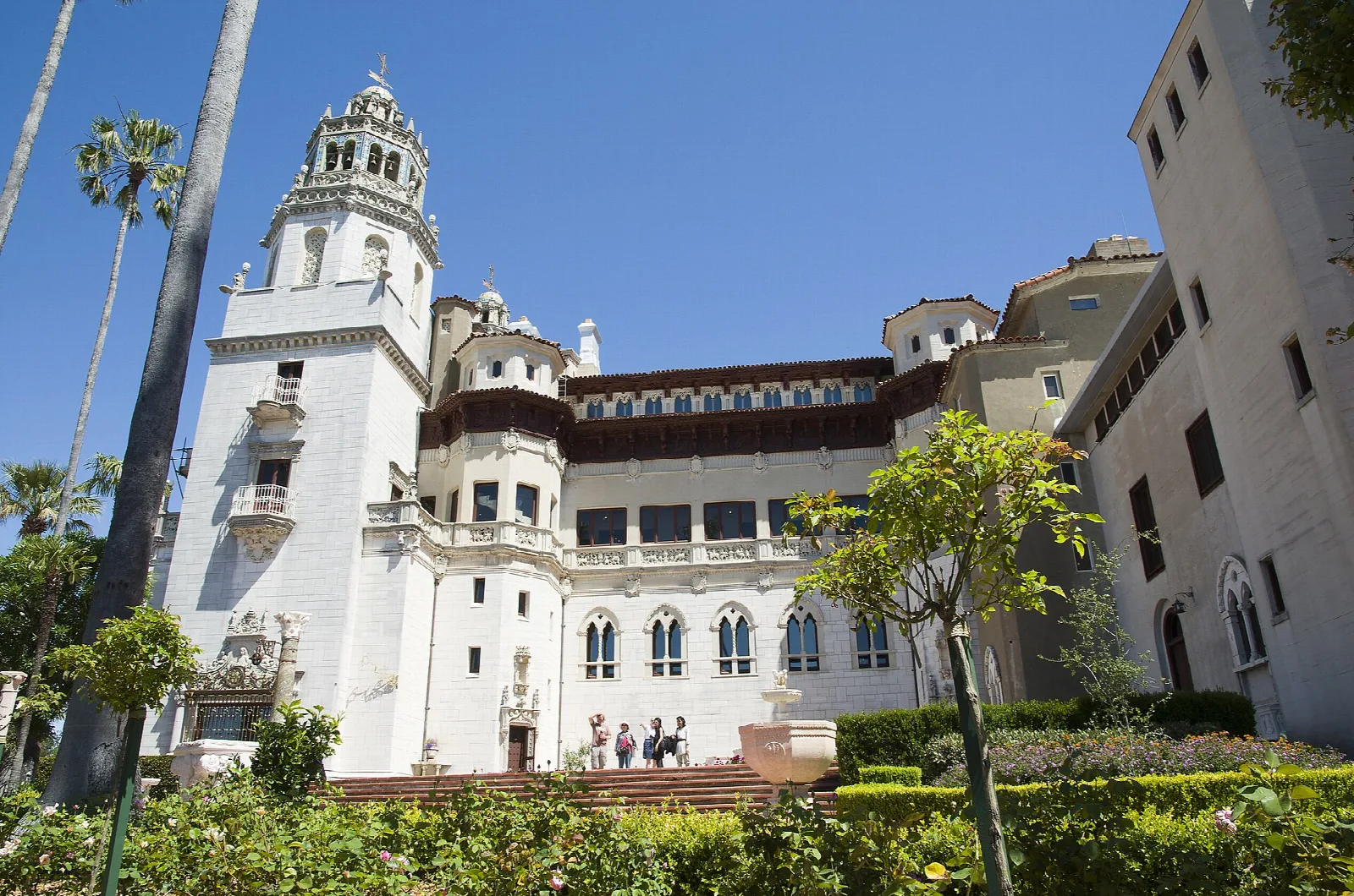 White castle tower and wings among gardens and palm trees