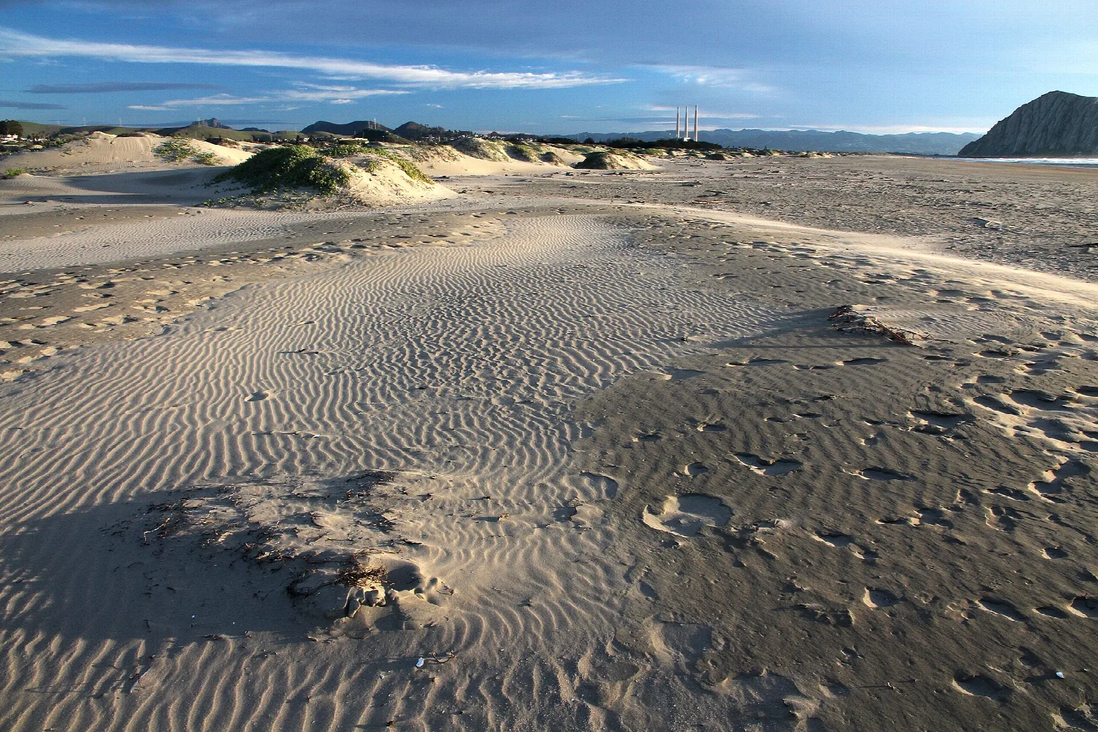 Rippled sand dunes and beach grass under a blue sky