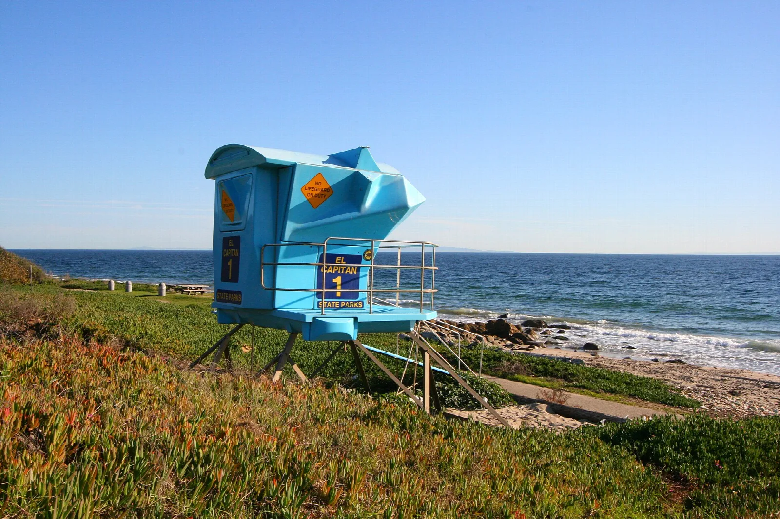 Blue lifeguard tower on a grassy bluff above the sea