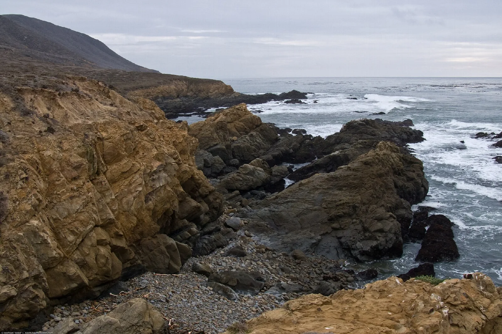 Golden sandstone cliffs above a rocky shore and ocean