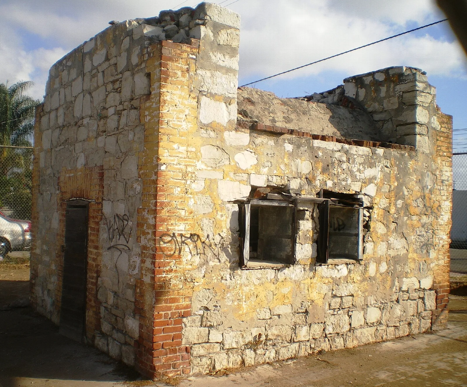 Small ruined stone building with brick edges and empty windows