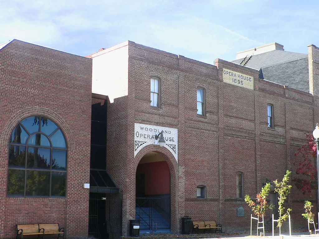 Red brick theater front with a large arched window and an arched entry