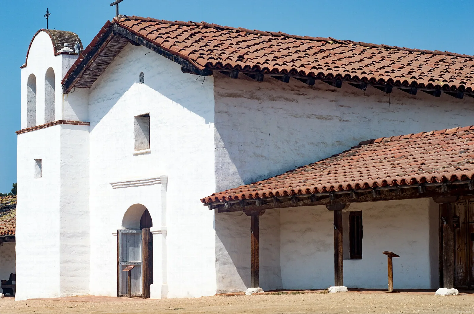 White adobe chapel with a red tile roof and a bell tower