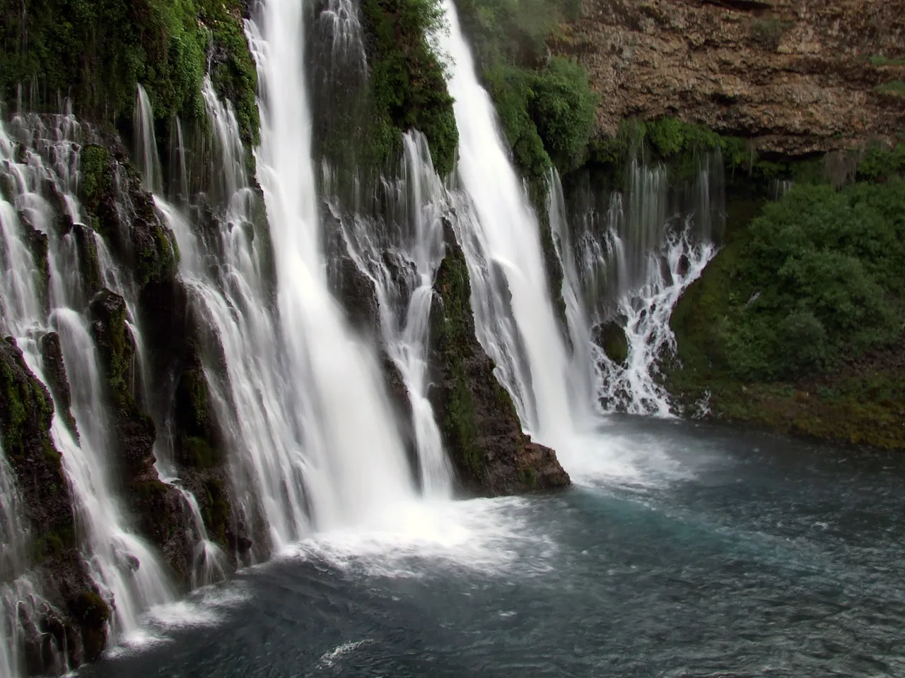 Waterfall streaming over a mossy cliff into a pool