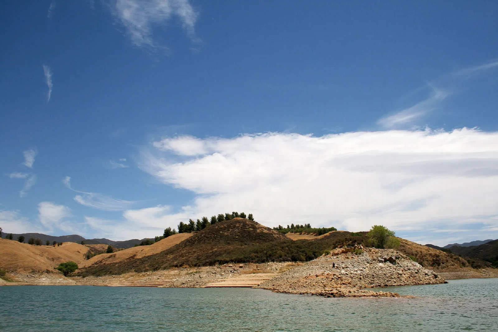 Lake water and a rocky point under a big cloud