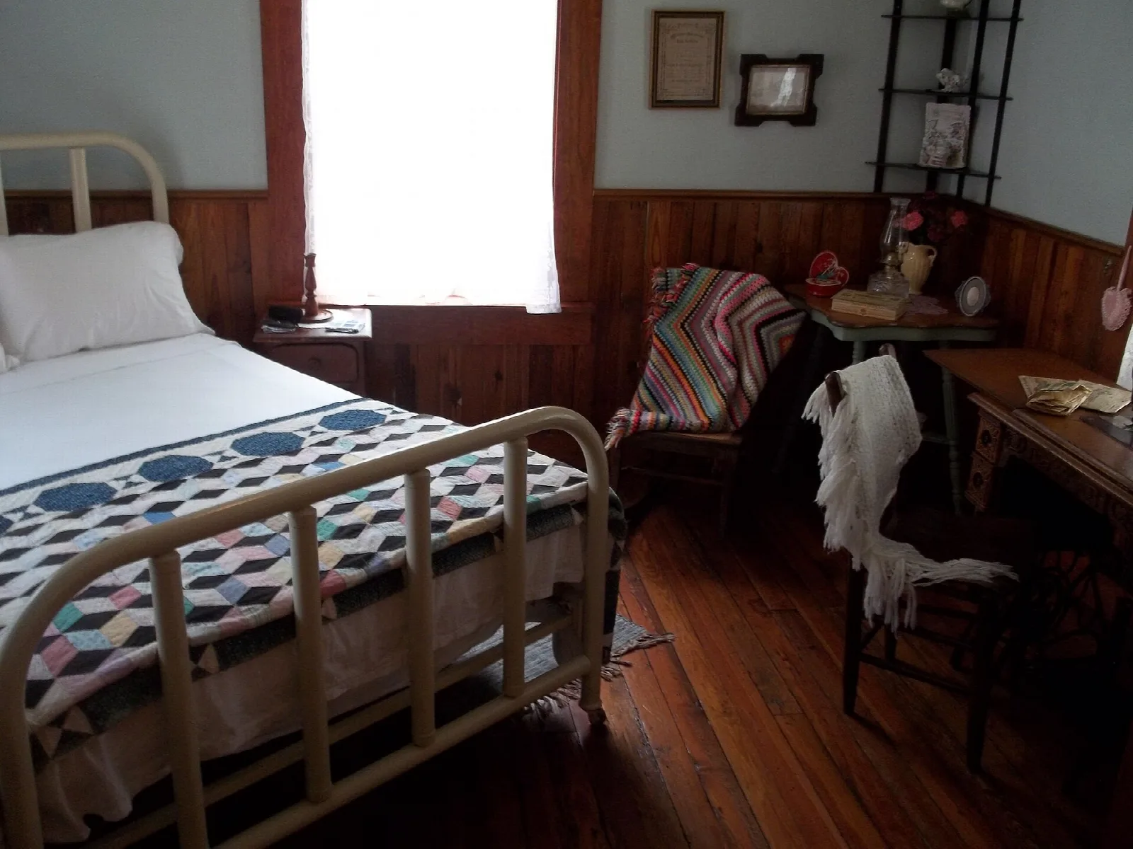 Old wooden bedroom with an iron bed and quilt