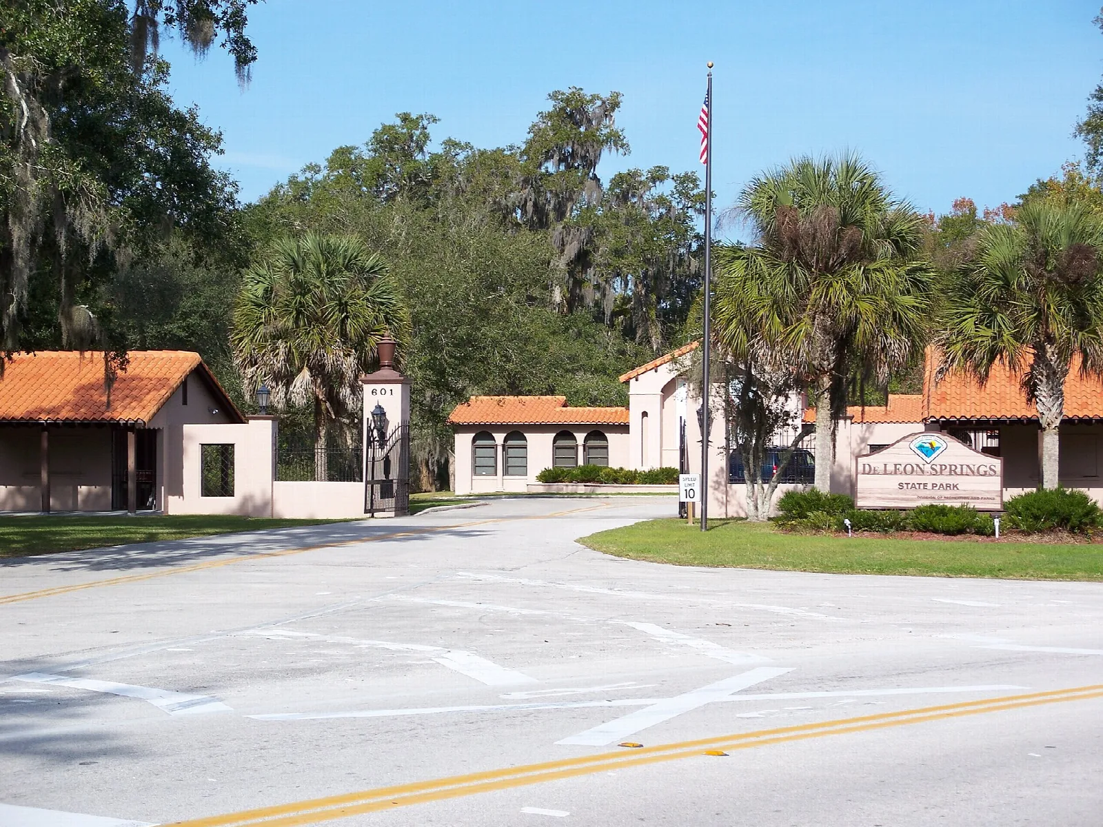 Park entrance with tiled-roof buildings, palms and oaks